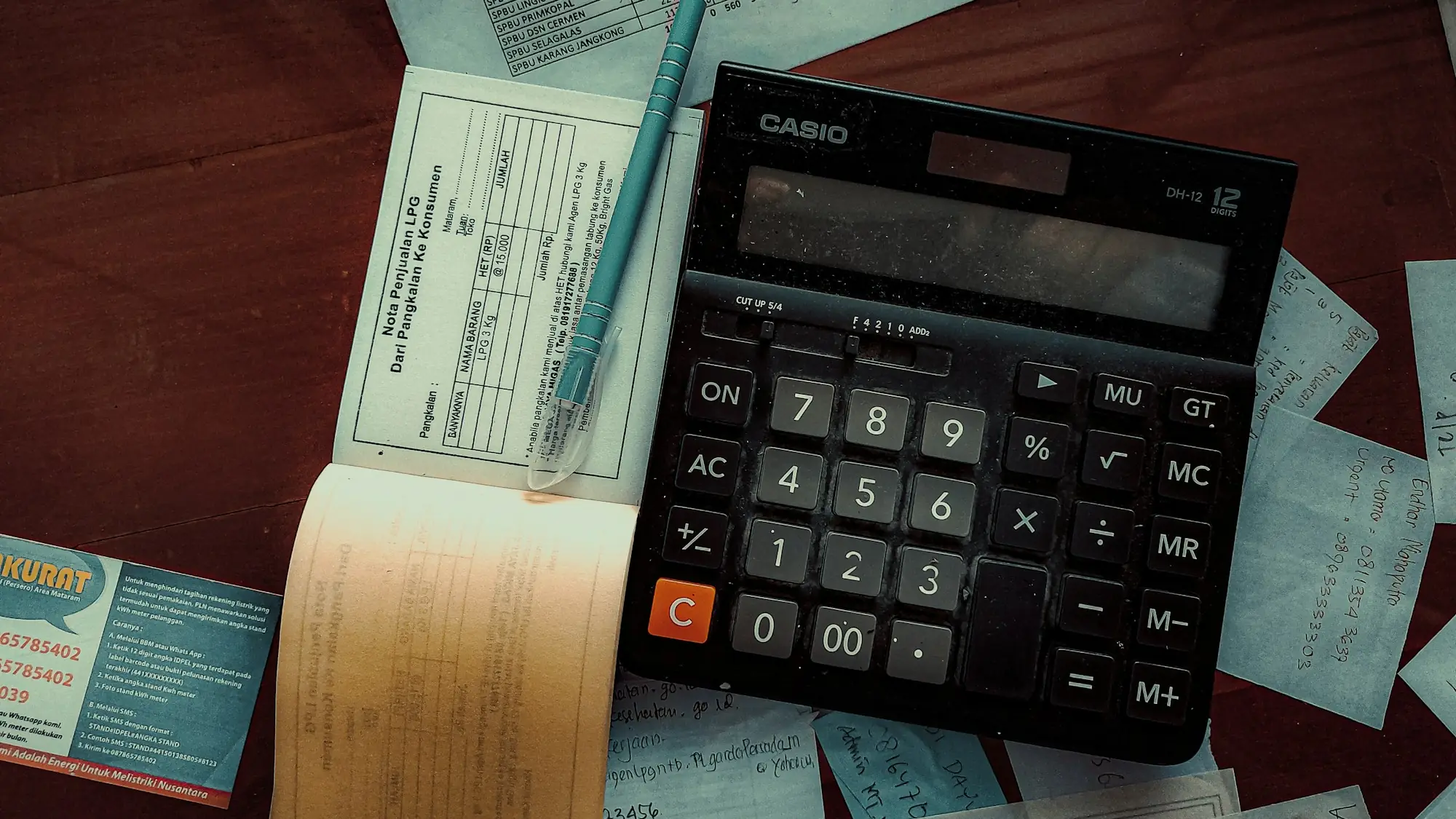 Calculadora, un bolígrafo y hojas de cálculo impresas sobre una mesa de madera