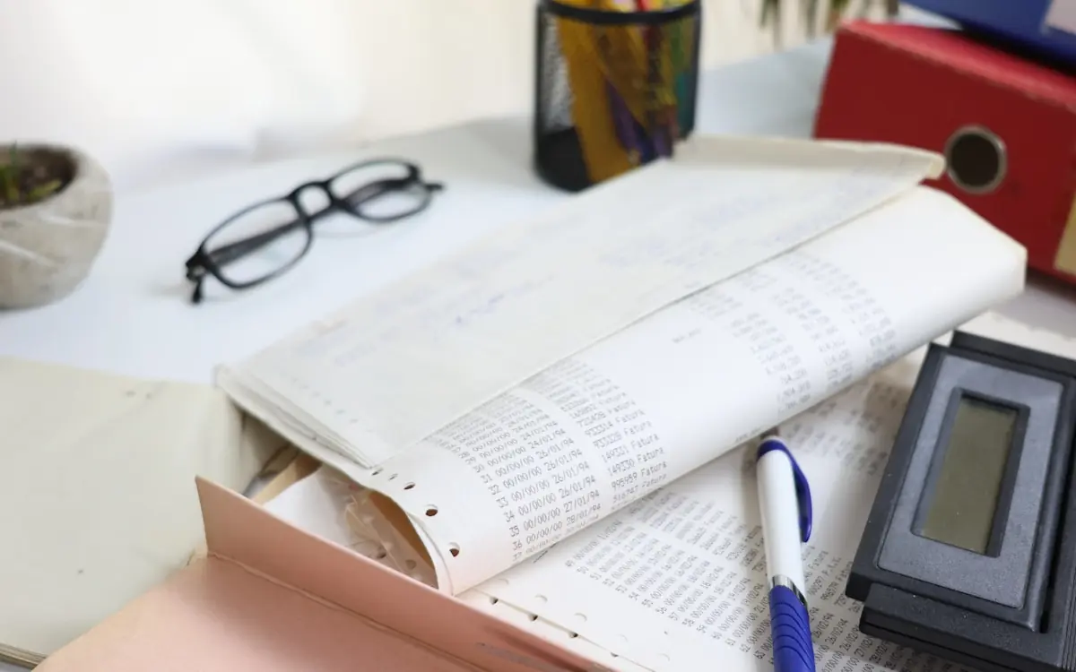 Listado contable impreso junto a unas gafas y un bolígrafo
