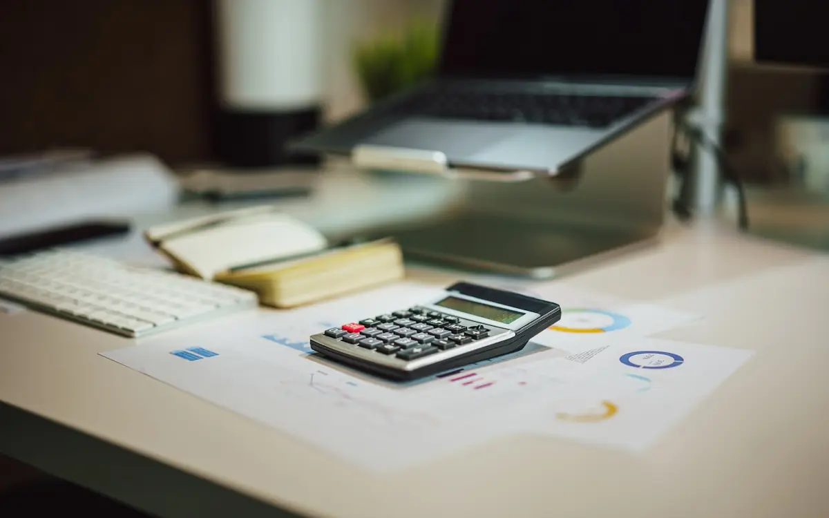 Calculadora, portátil y gráficos impresos sobre una mesa de trabajo